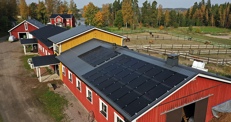 Aurinkopaneelit maatilarakennuksen katolla tuottavat energiaa