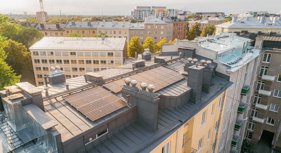 Korkealta kuvattu kuva Töölössä sijaitsevasta kerrostalosta, jonka katolla on aurinkopaneelit