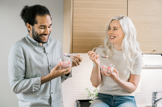 Two people are enjoying ice cream in a kitchen