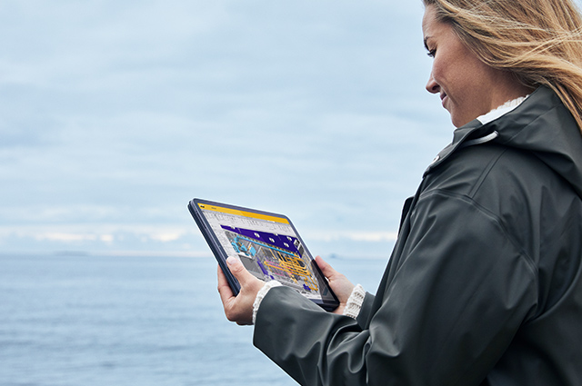A person is browsing a webpage on a tablet by a beach