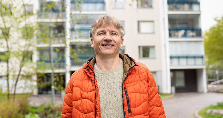 Poistoilmalämpöpumppuun tyytyväinen isännöitsijä seisoo kiinteistön edessä.