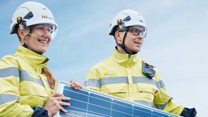 Kaksi Helenin työntekijää kantaa kädessään yhtä aurinkopaneelia